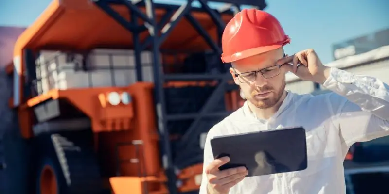 A worker looks at a tablet to determine if engineered crusher parts will help is mining operations