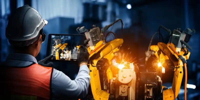 A worker scans heavy machinery using a tablet.